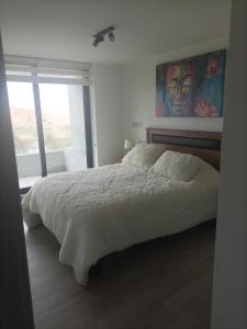 康康Hermoso Departamento dunas de concon的卧室配有一张床,墙上挂有绘画作品