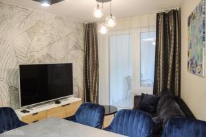比亚韦斯托克D Apartments Centrum Prowiantowa的客厅配有平面电视和蓝色椅子。