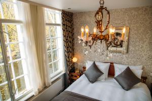阿姆斯特丹大使酒店的一间卧室配有一张带吊灯和窗户的床。
