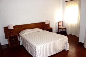 阿尔沃尔Clube Alvorférias的一间卧室设有一张床、一个窗口和一把椅子