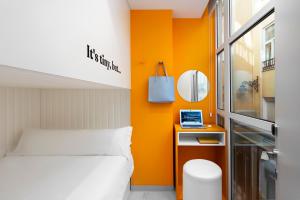 马拉加COEO Pod Hostel - Part of COEO Experience的一间卧室设有橙色墙壁和一张床