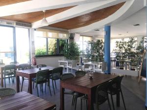 阿尔沃尔Clube Alvorférias的餐厅设有木桌、椅子和窗户。