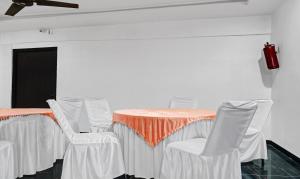瓦拉纳西Itsy By Treebo - Banana Boutique Varuna Bridge Varanasi的一张桌子、白色的椅子和橙色的桌布