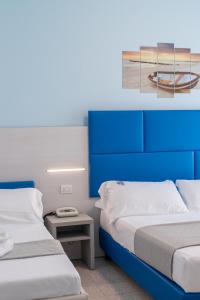 托尔托雷托大陆酒店的配有蓝色橱柜的客房内的两张床