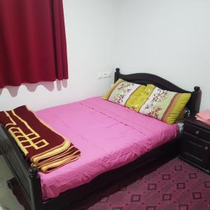 Id AÃ¯ssaHotel camping amtoudi的一间卧室配有一张带粉色床单的床和梳妆台。