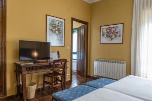 Perales del PuertoDON JULIO的一间卧室配有一张桌子、一台电视和一张床
