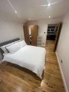 伦敦2 bedroom apartment in HampdenRd的卧室配有白色的床,铺有木地板
