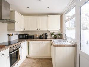 Penmaen-mawr6 Erasmus Street的厨房配有白色橱柜、水槽和窗户。