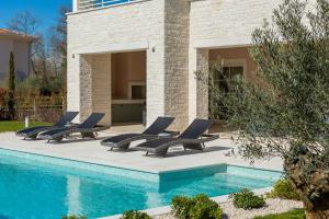 布罗托尼贾Villa Harmony by ILC (Istria Luxury Collection)的游泳池旁的一排躺椅