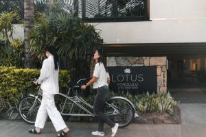 檀香山Lotus Honolulu at Diamond Head的两名妇女骑着自行车在大楼前行走