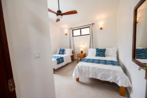 MsambweniOasys House - Beautiful Private Beach Front Home的一间卧室配有两张床和吊扇