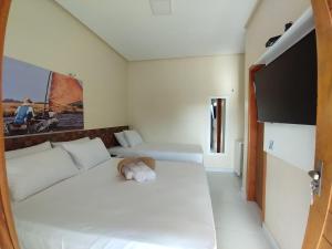 Paulino NevesPOUSADA DOS LAGOS的卧室配有一张白色的床,上面有一只动物填充物