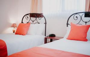 PotrerillosFrenold Inn的两张带橙色和白色枕头的床