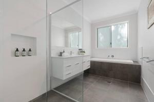 Callala BayThe Quarterdeck的白色的浴室设有淋浴、浴缸和水槽。
