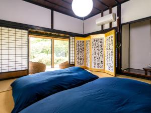 镜野さいの郷「椛」的一间设有蓝色床的卧室,位于带窗户的房间内