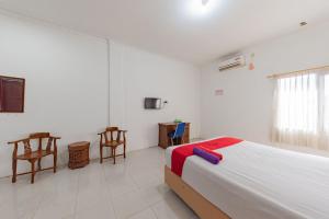 沙马林达RedDoorz near Samarinda Square的卧室配有一张床和一张桌子及椅子