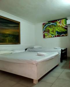 卡塔赫纳Hostal Tosty的一间卧室设有两张床,墙上挂着一幅画