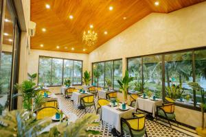 潘切Perolas Villas Resort Powered by ASTON的一间设有桌椅的餐厅,位于带窗户的房间内