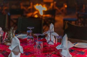 马赛马拉Mara Elatia Camp的一张桌子,上面有红桌布,上面有眼镜和餐巾