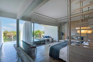 华欣Cape Nidhra Hotel的一间卧室设有一张床和一个大型玻璃墙