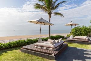 华欣Cape Nidhra Hotel的海滩上的2把躺椅和1把遮阳伞