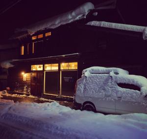白川村GuestHouse Shirakawa-Go INN的建筑物前的雪覆盖的汽车