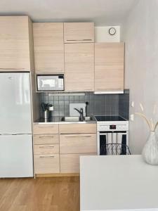 赫尔辛基Lovely studio in the famous Design District area.的厨房配有木制橱柜和白色冰箱。