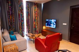 金沙萨Sultani Hotel的客厅配有红色椅子和电视
