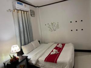 琅勃拉邦Jasmine Place House的一间卧室配有一张带红白毯子的床
