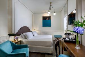 马德里女王别墅H10精品酒店的一间卧室配有一张床和两张蓝色椅子