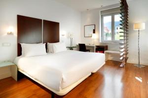 圣洛伦索-德埃斯科里亚尔埃克维多利亚酒店的卧室设有一张白色大床和一扇窗户。