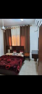 亚喀巴Abo Amer Apartments的一间卧室配有红色的床和钢琴