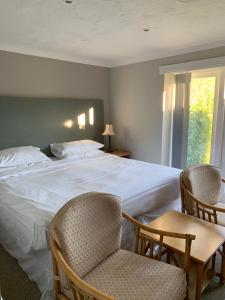 温坎顿Holbrook Manor & Spa - OCEANA COLLECTION的一间卧室配有一张大床和两把椅子