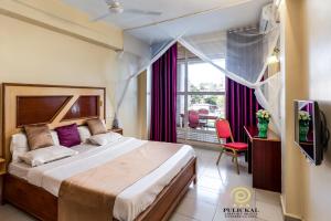 恩德培Pulickal Airport Hotel的一间卧室设有一张大床和一个大窗户