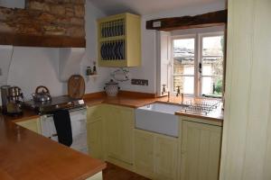 洛尔斯劳特Riverside Cottage的厨房配有黄色橱柜和白色水槽