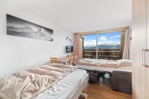 安塞热Chaleureux studio à Anzère, accessible à ski, proche de tout的客房设有两张床、一张桌子和一扇窗户。