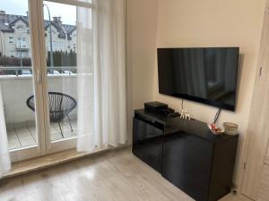 格丁尼亚Modern Box Apartment的客厅配有平面电视和窗户。