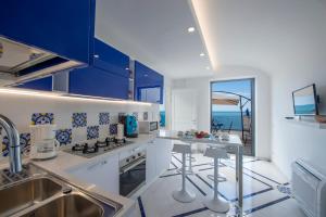 弗洛里La Perla di Nettuno的一间设有蓝色橱柜的厨房,享有海景