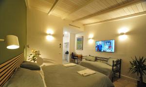 维泰博Tenuta Bussete Country Hotel的一间带两张床、一张沙发和一台电视的卧室
