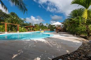 福尔图纳Arenal History INN的棕榈树度假村的游泳池