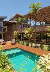 普腊亚罗萨Pousada Rosa Tropicalia的一个带木甲板和房子的游泳池