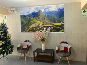 利马HOTEL ESTRELLA的圣诞树和两把椅子,墙上一幅画
