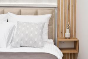 诺维萨德Divine & Delight Apartments的一张铺有白色床单的床和床头柜上的花瓶