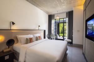 清迈Hotel Ping Silhouette的卧室配有一张白色大床和电视。