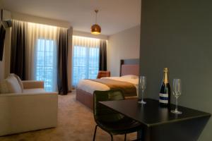 普里什蒂纳Downtown Apartments的酒店客房,配有一张床和一张桌子,并提供一瓶香槟