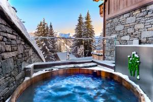 谷雪维尔Lys Martagon的雪中建筑物边的热水浴池