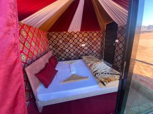 瓦迪拉姆Desert shine camp的红色枕头帐篷内的一张床位