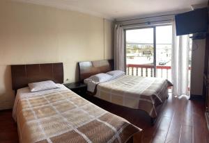 昆卡ALOJAMIENTOS HOSTAL REST HOUSE的配有窗户的酒店客房内的两张床