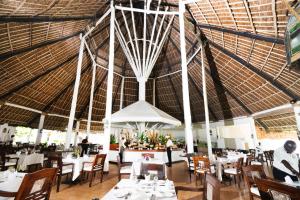 马林迪Sandies Malindi Dream Garden的餐厅设有白色的桌椅和大型天花板。