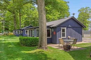 NewaygoPet friendly cabin with dock, firepit, grill, bikes的院子里带桌椅的蓝色棚子